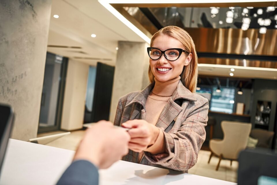 Young woman in hotel check in at reception or front office being given key card